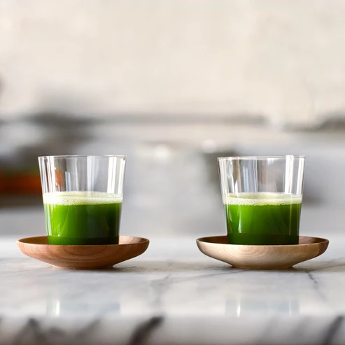 A_pair_of_Matcha_Shot_Glasses_and_Wooden_Saucers_full_of_vibrant_green_matcha_shots.webp